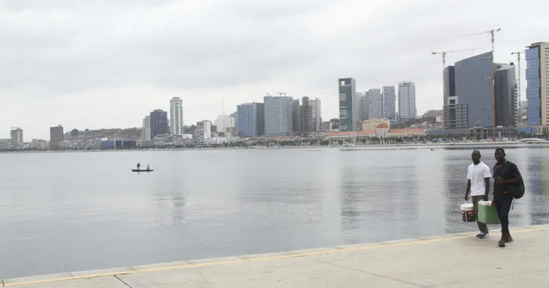 Baía de Luanda , dois jovens com caixa térmica passando pela marginal